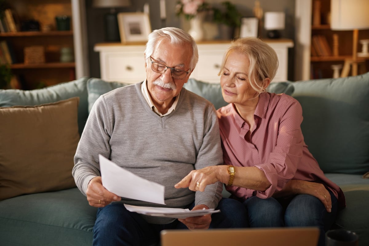 Elderly couple reviewing estate planning documents together on a sofa